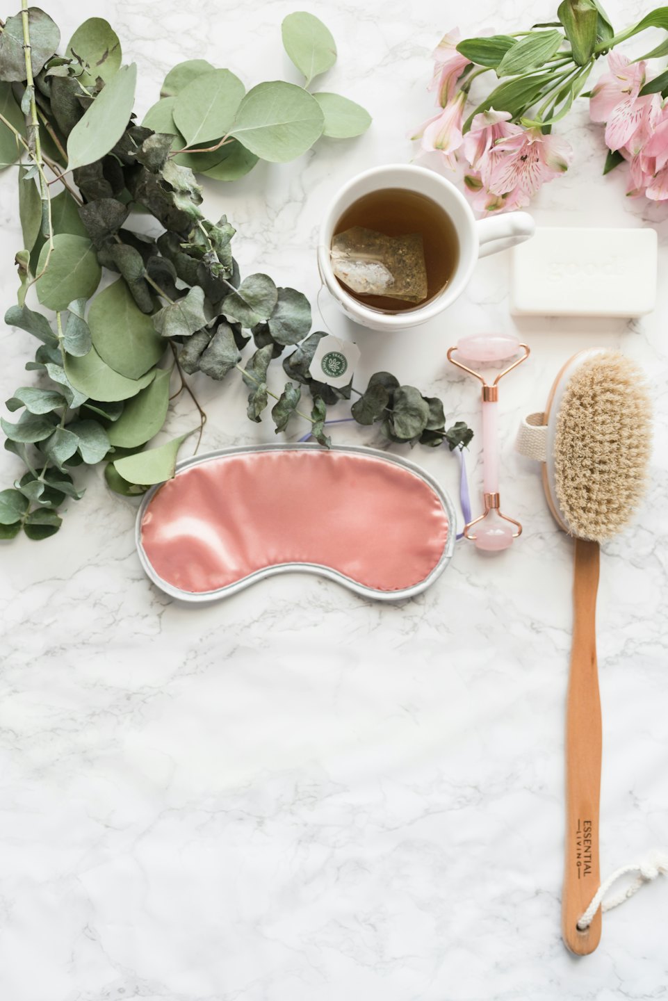 Self-care items laid out on a white marble surface.